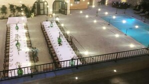 Een terras met eettafels, een zwembad en een gebouw met een bakstenen gevel.
