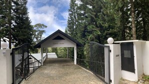A gated entrance to a building labeled "Green Acres" with a gravel path leading to a covered area. - Green Acres Fraser's Hill (Raub)