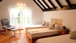 A room with two beds, a chair, a nightstand, and a window with curtains. - Green Acres Fraser's Hill (Raub)