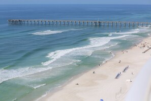 A beach with a pier extending into the ocean.