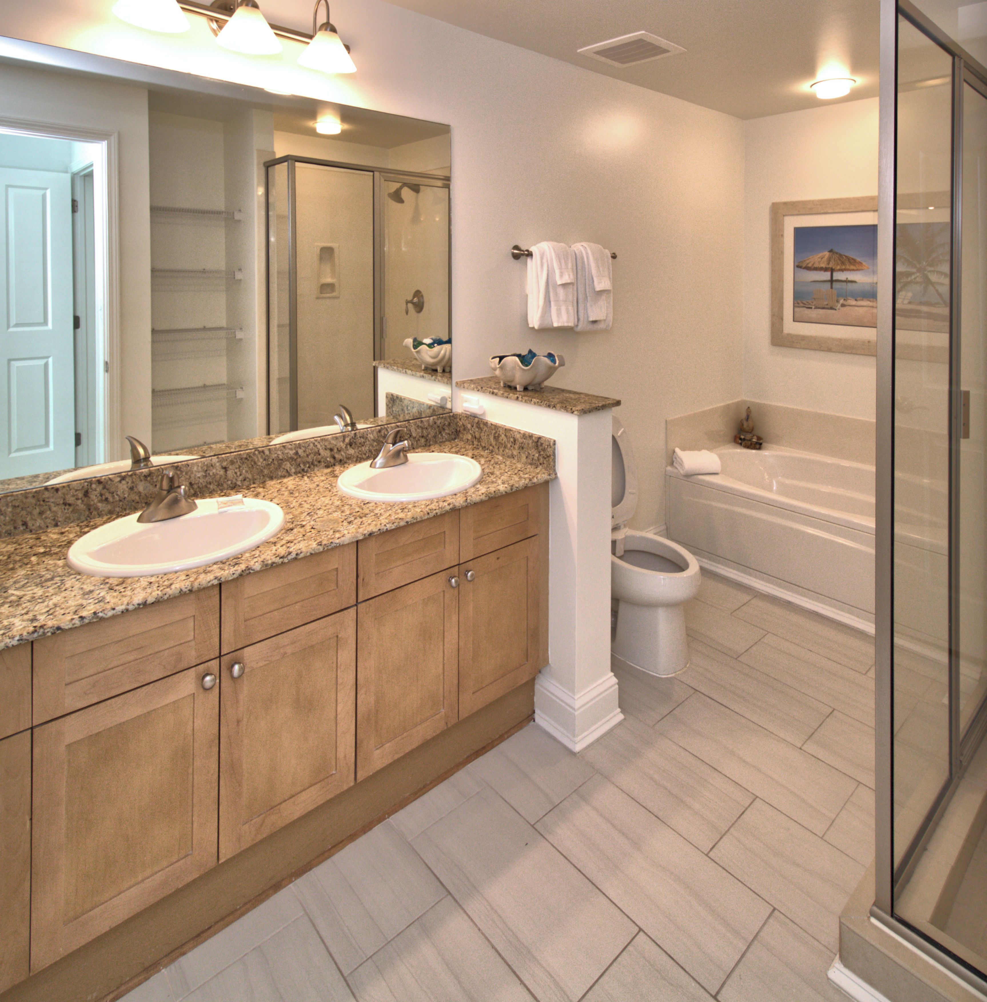 A bathroom with two sinks, a bathtub, and a shower.
