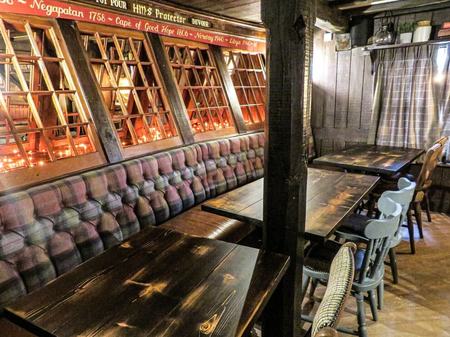 A restaurant with wooden tables and benches, a stone wall, and a decorative window display.