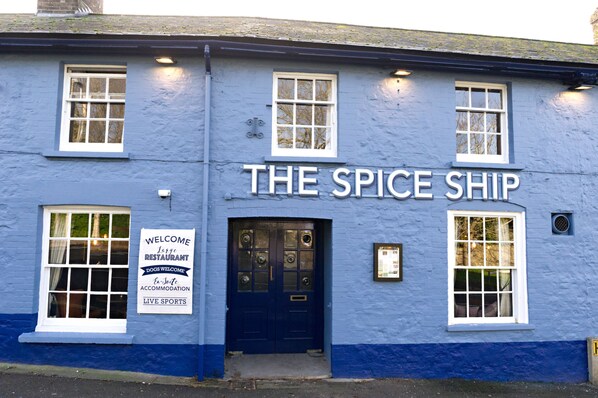 A building with a sign reading "THE SPICE SHIP" and a welcome sign for a restaurant, accommodation, and live sports. - The Spice Ship (Weymouth)