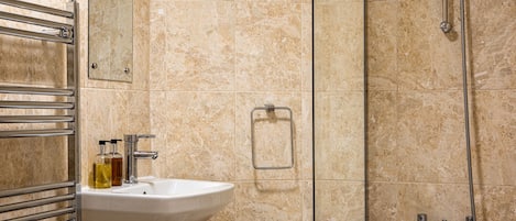 A bathroom with a sink, mirror, towel rack, and shower.