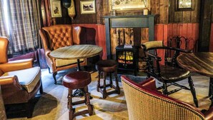 A cozy room with a fireplace, leather armchairs, a round table, and a wicker chair. - The Spice Ship (Weymouth)
