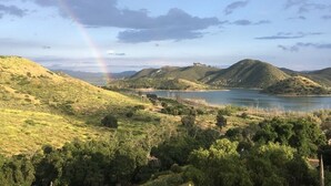 Eine Landschaft mit sanften Hügeln, einem See und einem Regenbogen.