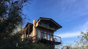 Eine Holzhütte mit Balkon, umgeben von Bäumen und Sträuchern.
