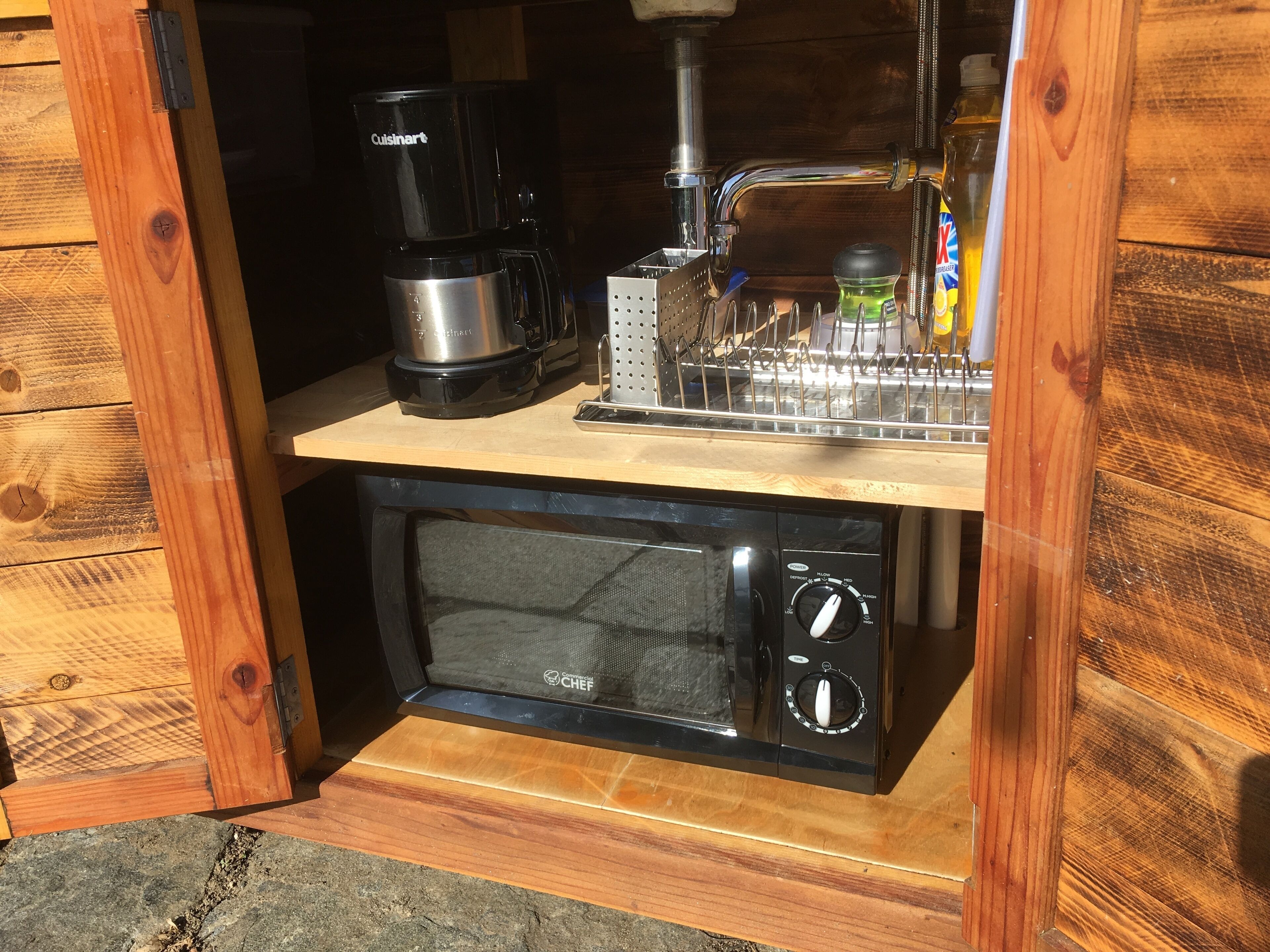 A compact kitchen area with a coffee maker, a microwave, and a utensil holder.