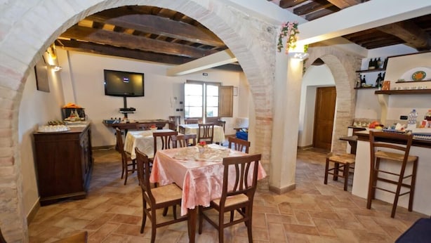 A dining area with a table set for four, surrounded by wooden chairs, under a vaulted ceiling with exposed beams. - B&B Madonna Del Latte (Cannara)