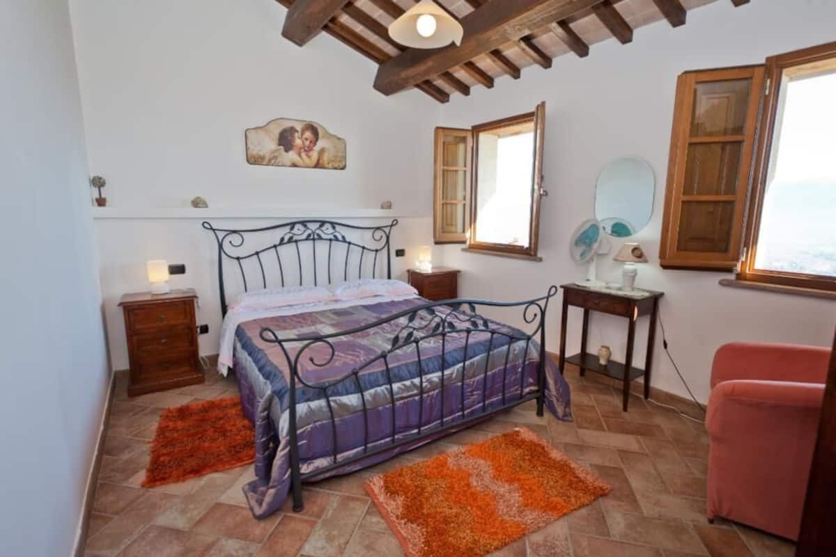 A bedroom with a bed, two nightstands, a wooden cabinet, a window, and a mirror.
