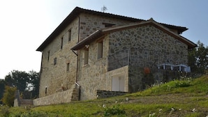 A stone building with a sloped roof, a balcony with a metal railing, and a staircase leading to the entrance. - B&B Madonna Del Latte (Cannara)