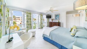 Habitación de hotel con balcón, cama, escritorio y televisor.