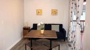 A room with a wooden dining table, a sofa, and two flower paintings on the wall. - Rainier Guesthouse (Walk to Metro) (Seattle)