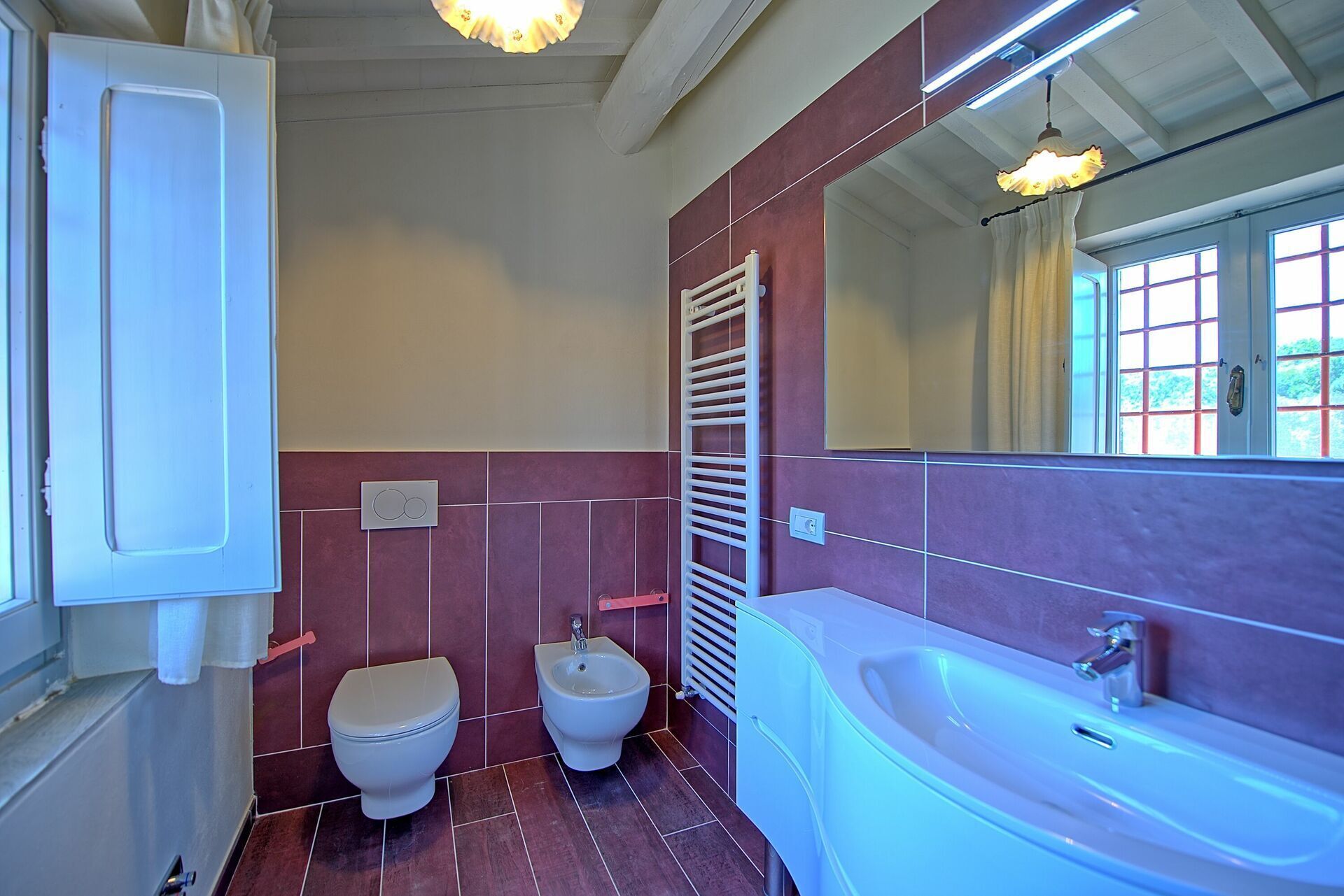 A bathroom with two toilets, a bidet, a bathtub, and a large mirror.