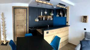 Eine moderne Küche mit einer Holztischinsel, blauen Stühlen und Pendelleuchten.