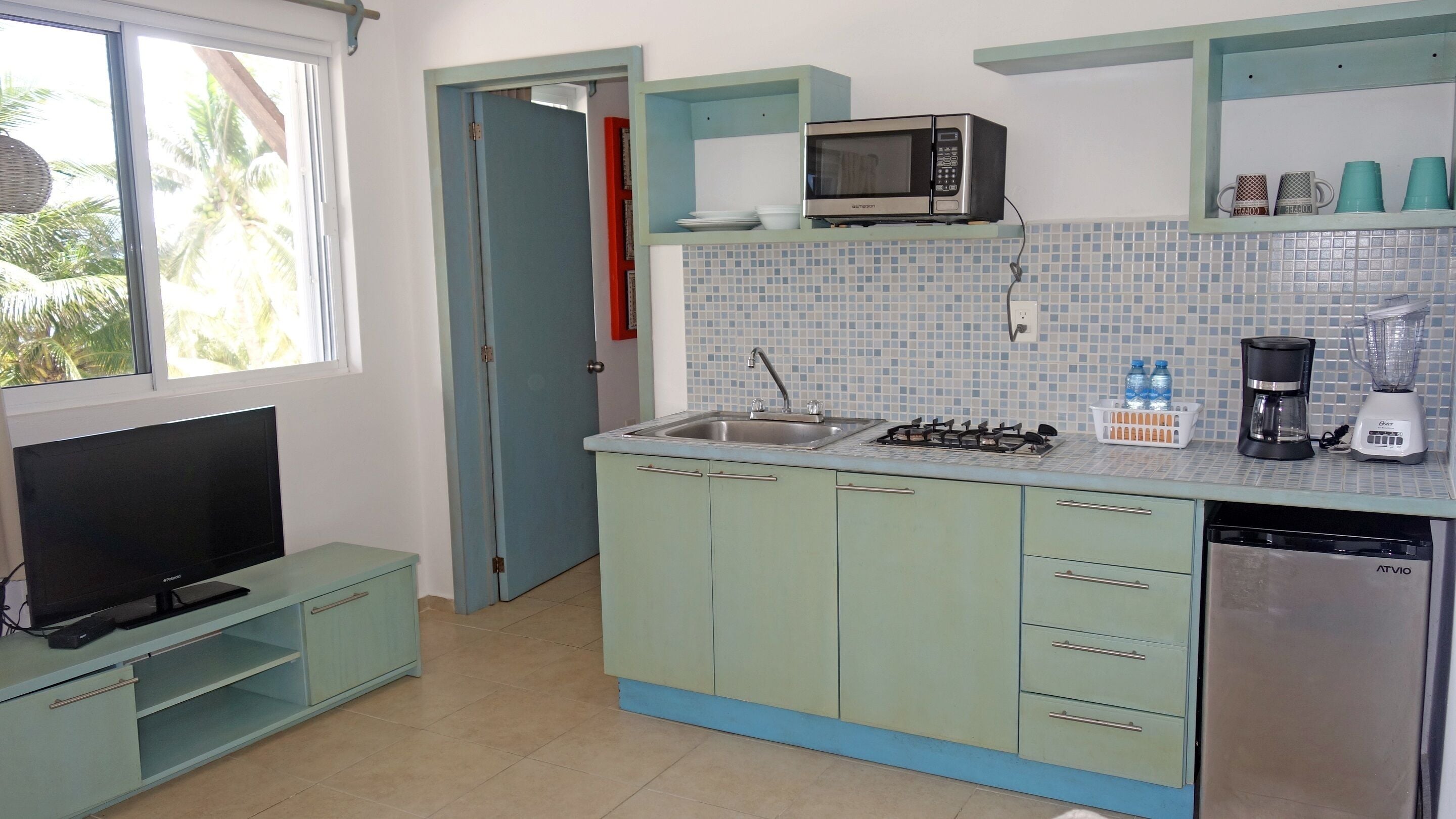 A compact kitchen with a TV, microwave, sink, stove, and dishwasher.