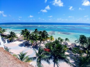 A beach resort with palm trees, clear blue waters, and a view of the ocean. - El Fuerte Beach Resort (Mahahual)