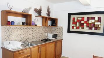 A kitchen with wooden cabinets, a tiled backsplash, a microwave, and a sink.