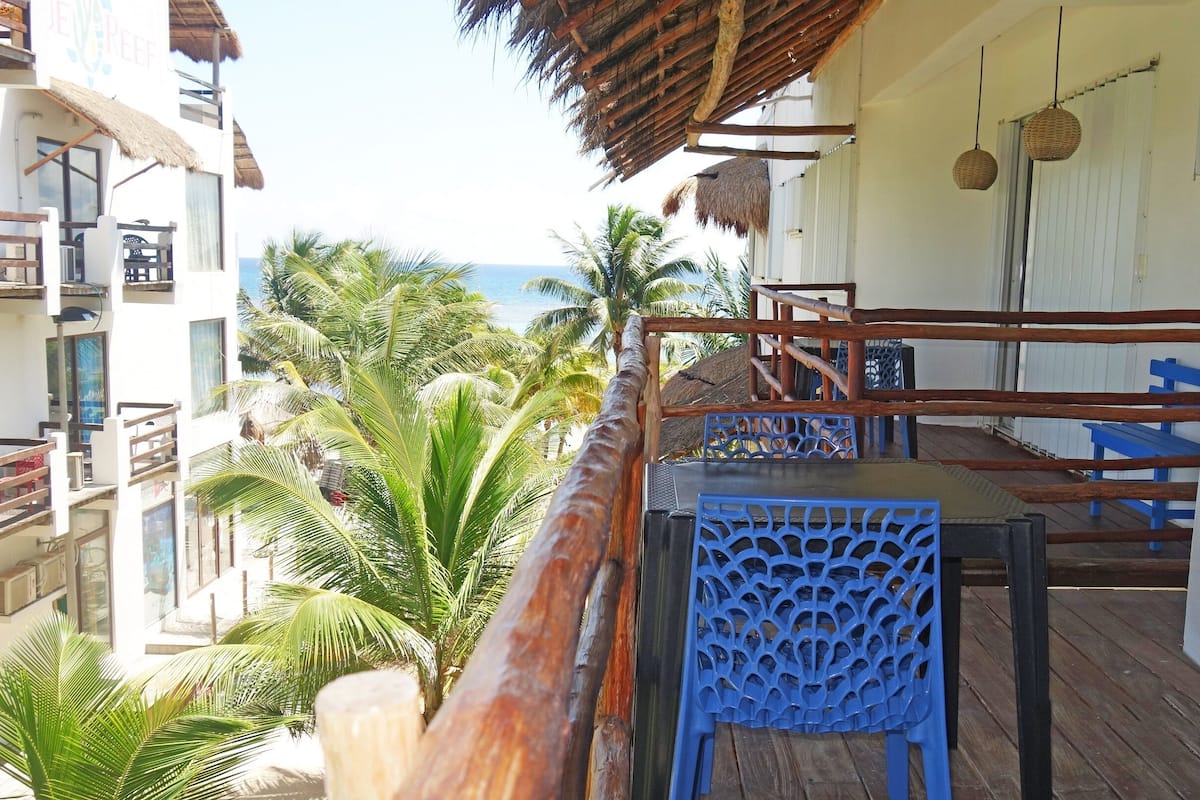 A balcony with a wooden railing, a blue chair, and a table.