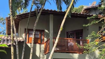 A two-story building with a balcony, surrounded by palm trees and a paved pathway.