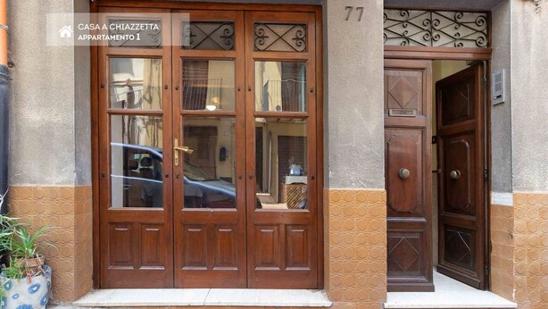 En entré med två dörrar och en skylt med texten ”CASA A CHIAZZETTA, LÄGENHET 1”.