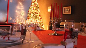 Een eettafel gedekt voor een maaltijd, met een kerstboom op de achtergrond.