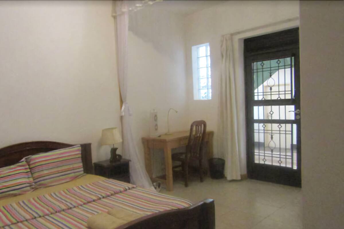 A bedroom with a bed, a desk, and a chair.