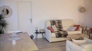 A modern living room with a wooden dining table, white sofa, and a small side table.