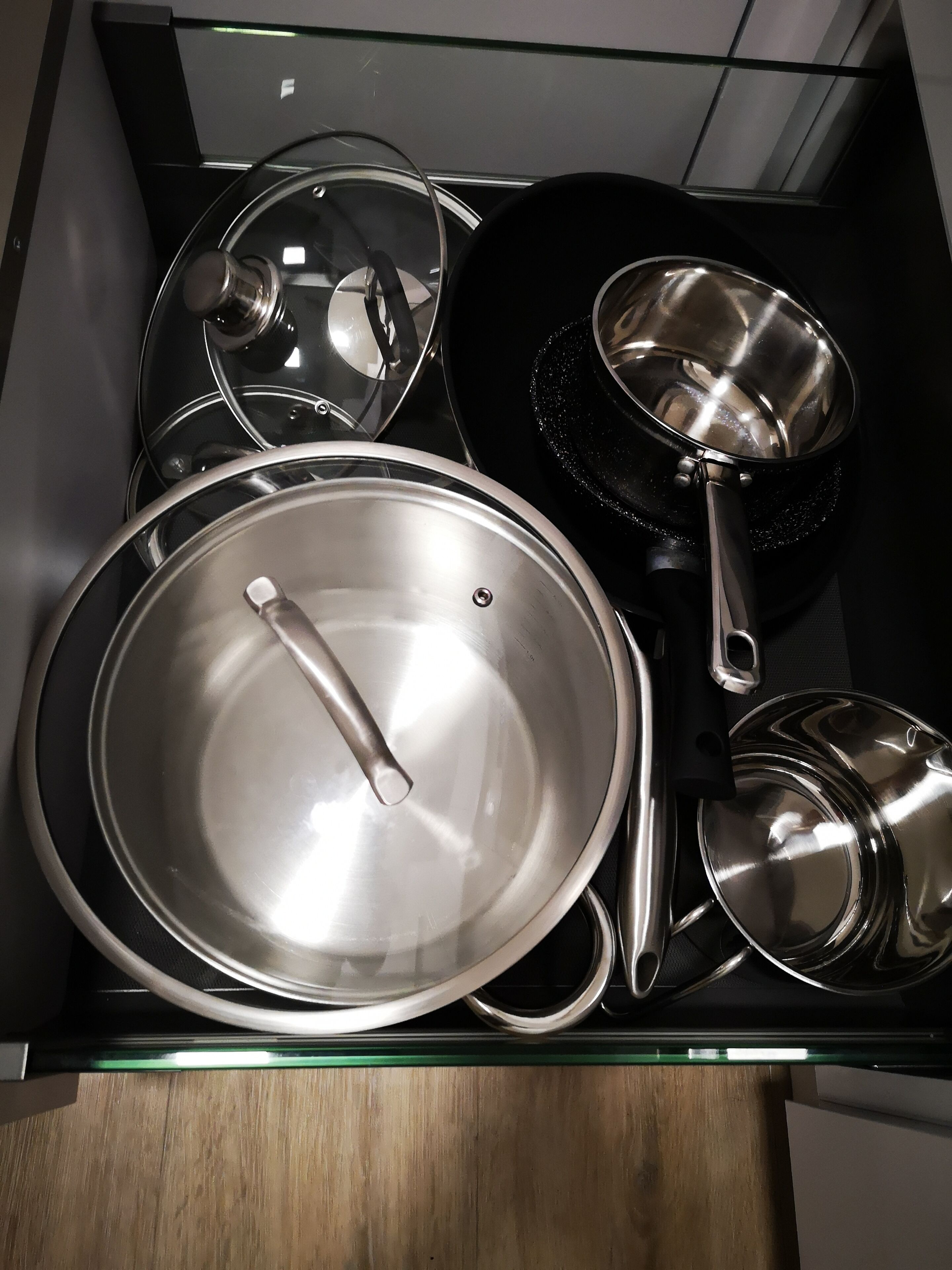 A kitchen with stainless steel cookware including pots, pans, and a frying pan.