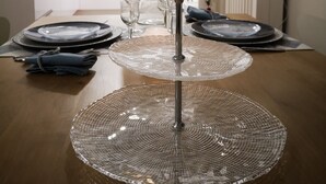 A dining table set with plates, glasses, and cutlery in a modern kitchen with white cabinets and a visible oven.