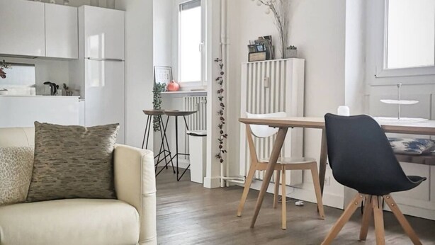 A modern living room with a sofa, a coffee table, and a dining area with a table and chairs.