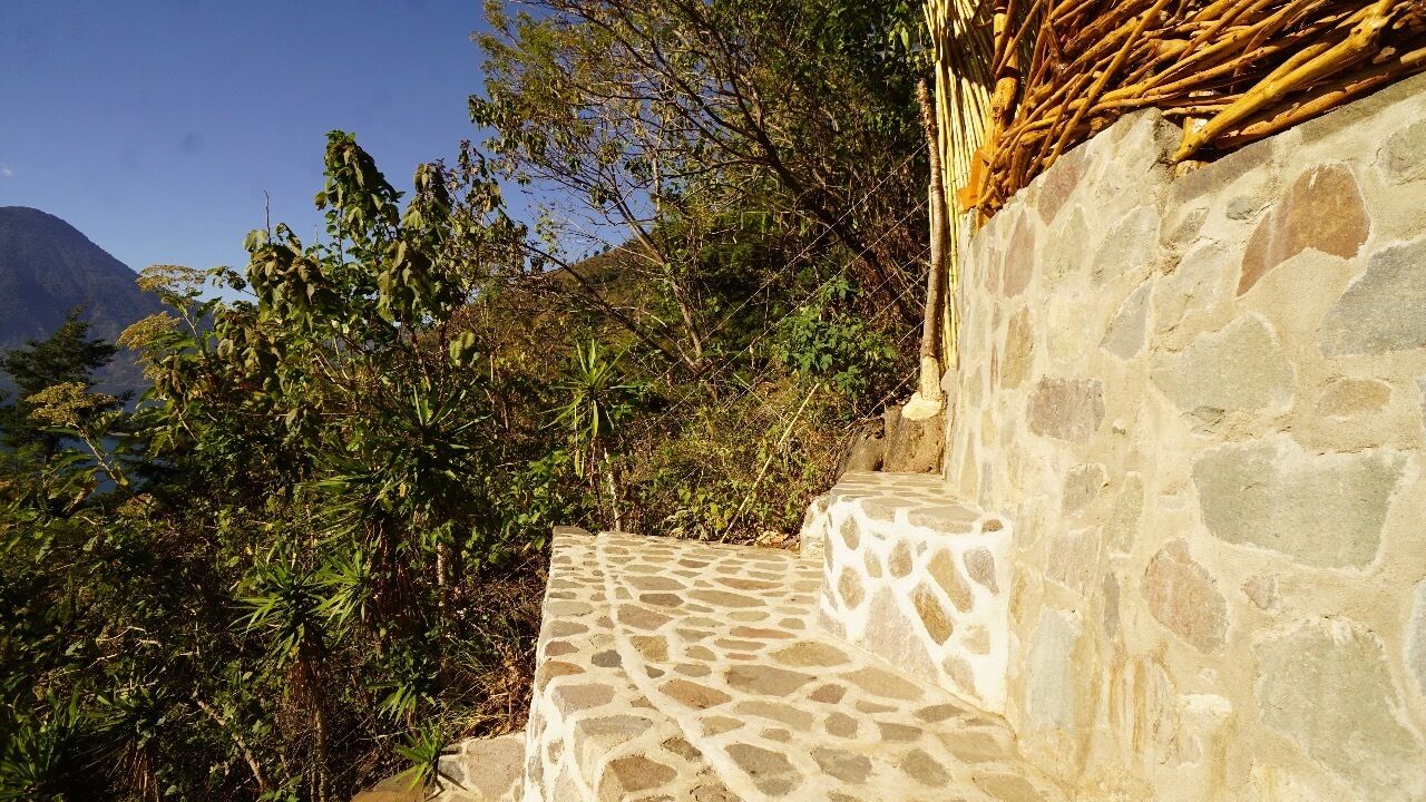 A stone staircase leading up to a stone building with a thatched roof.