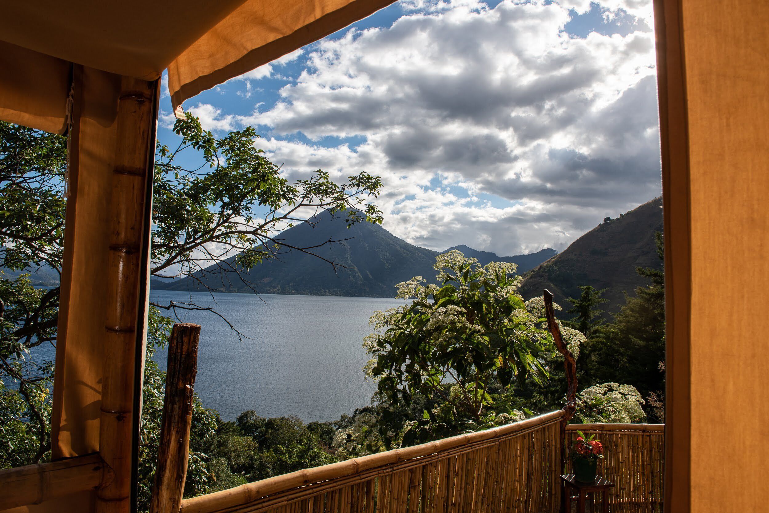 Un balcón de madera con vista a un lago y montañas.