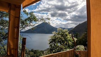 Un balcón de madera con vista a un lago y montañas.