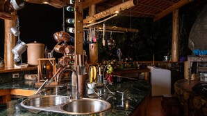 A kitchen with a marble countertop, stainless steel sink, and hanging utensils. - El Picnic Atitlan (Santa Cruz La Laguna)