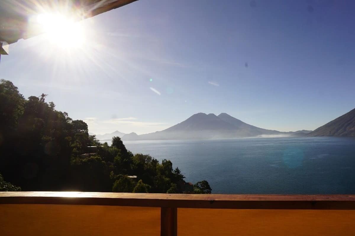 A view from a balcony overlooking a mountain and a body of water.