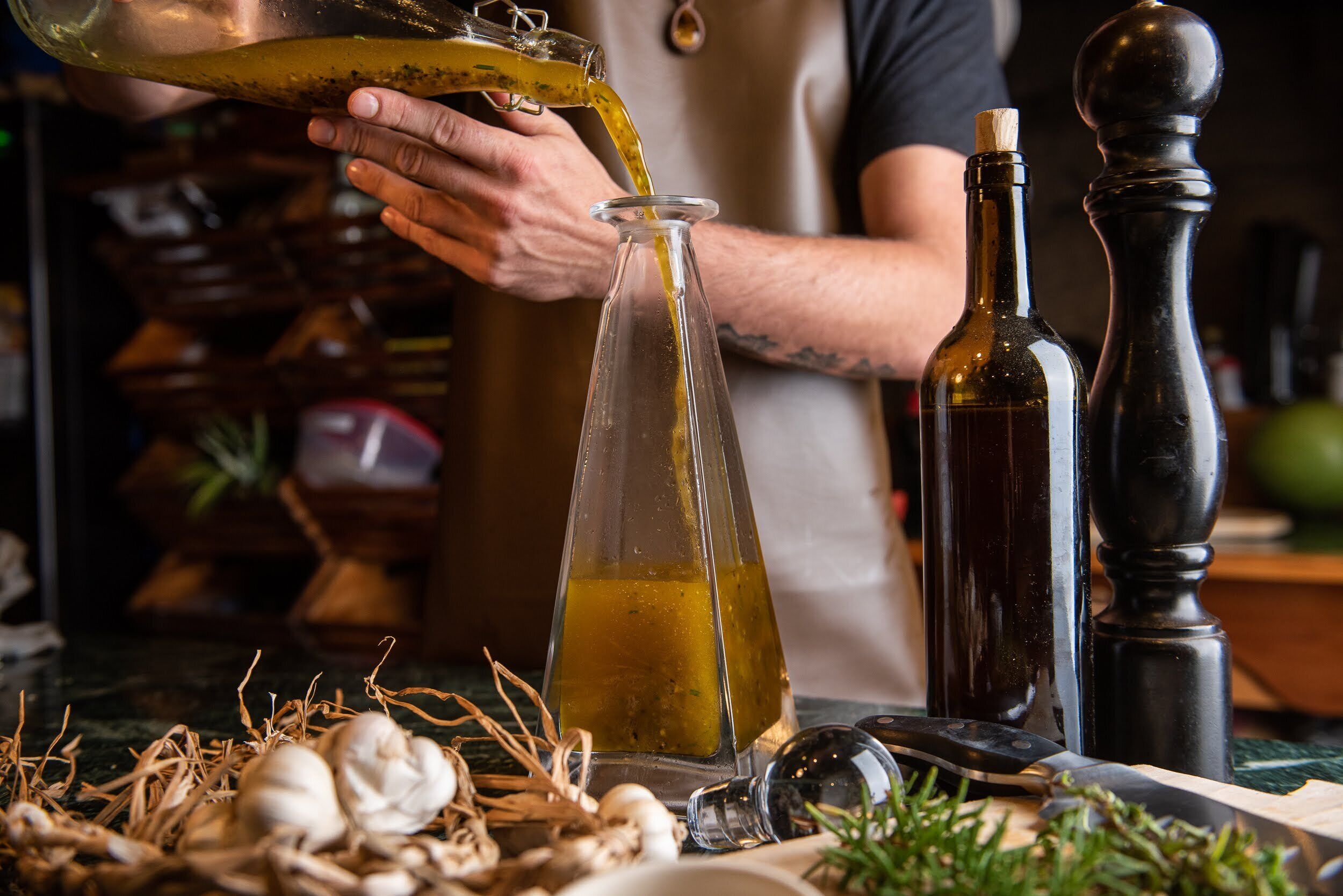 Une personne verse de l’huile d’olive dans une bouteille en verre.