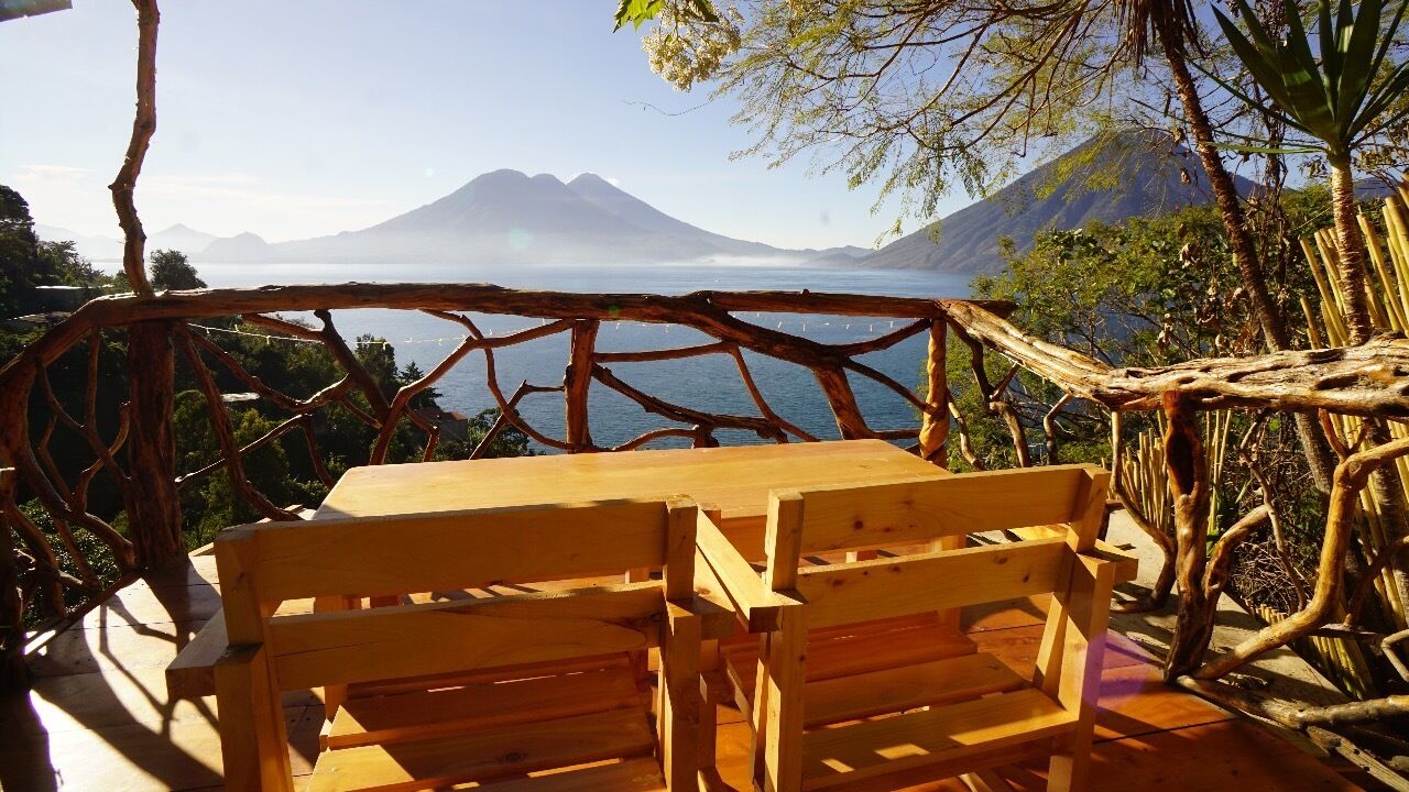 A wooden table and bench overlooking a lake with mountains in the background.