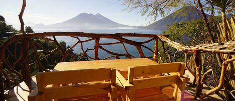 A wooden table and bench overlooking a lake with mountains in the background.