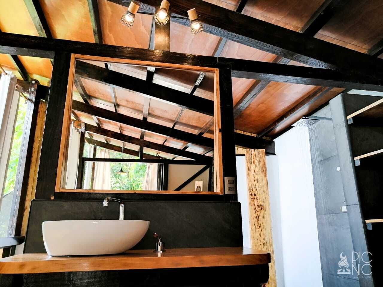 A modern bathroom with a large mirror, wooden beams, and a vessel sink.