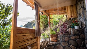 A wooden bench under a wooden pergola with a stone wall and potted plants. - El Picnic Atitlan (Santa Cruz La Laguna)
