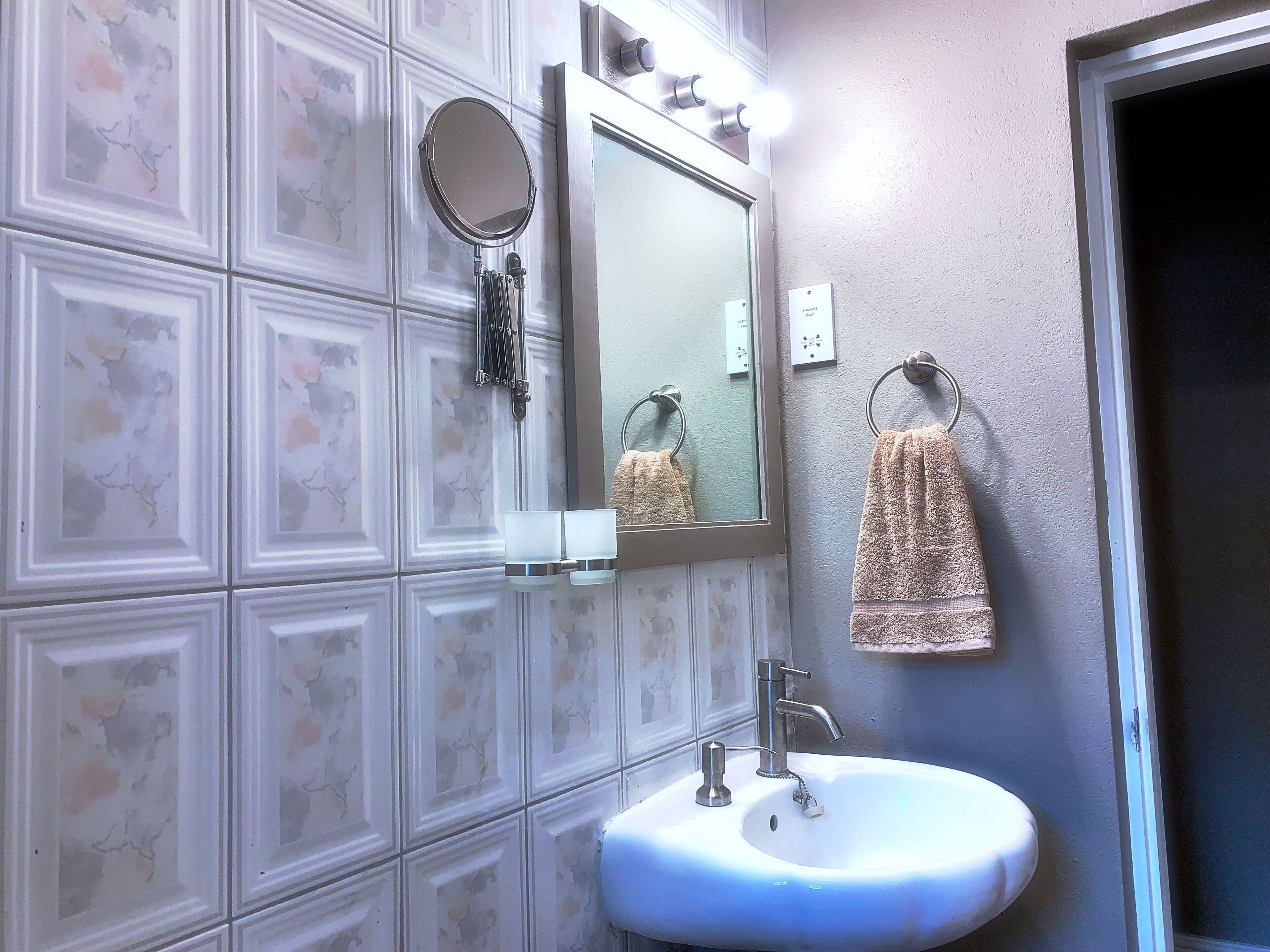 A bathroom with a white sink, a mirror, and a towel rack.