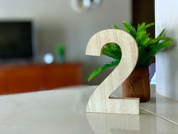 A wooden number '2' on a reflective surface with a potted plant beside it. - Large 3 Bed + FREE amenities + Close to everything (Brighton)