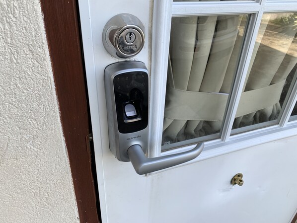 A door with a keyhole, a door handle, and a window with curtains.