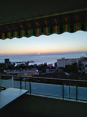 Varanda com vista para a paisagem urbana costeira ao pôr do sol.