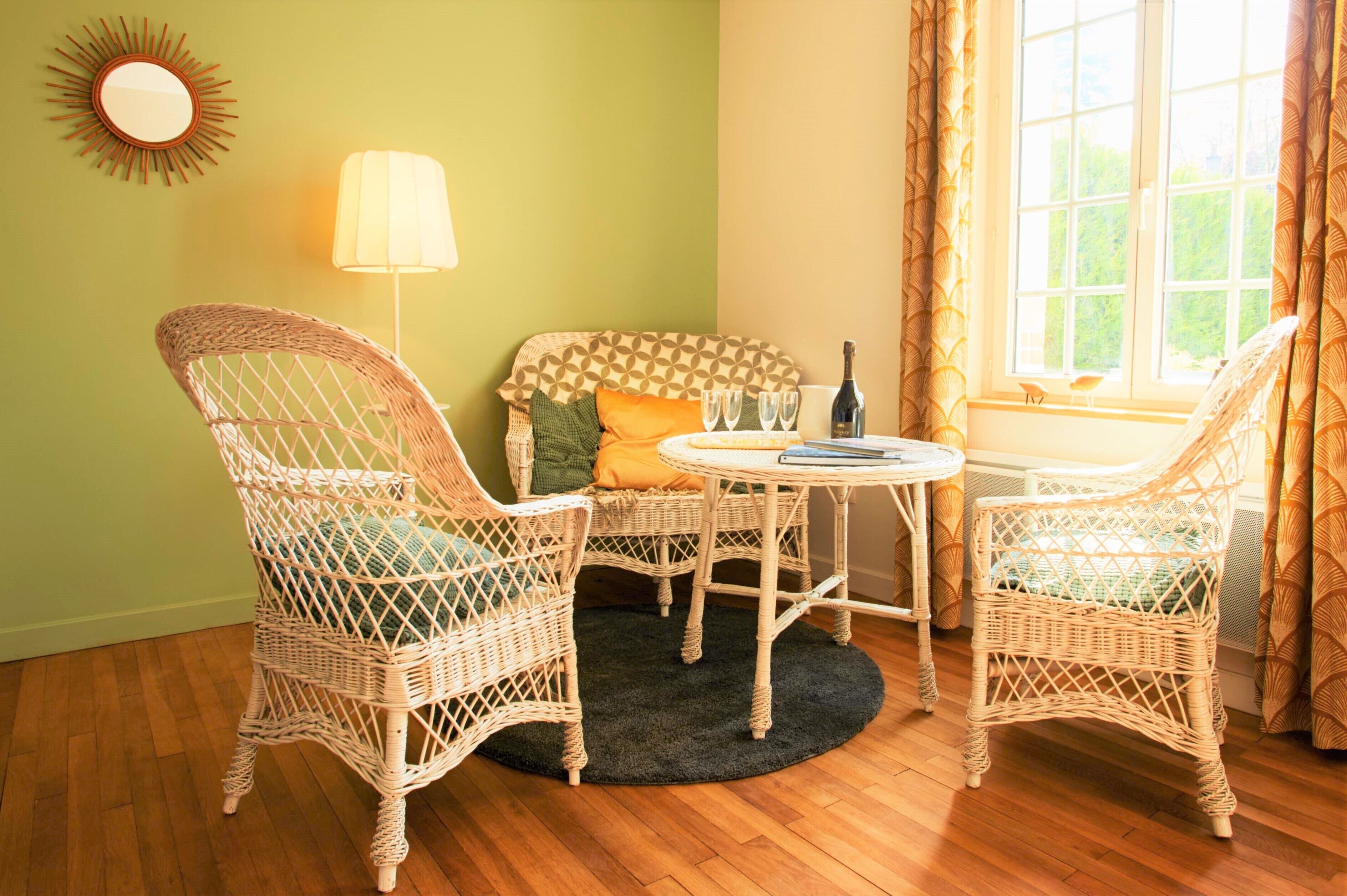 Une pièce chaleureuse avec des fauteuils en osier, une table ronde et un canapé agrémenté de coussins à motifs.