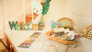 Un panneau d’accueil, un panier en bois rempli de brochures et une carte posée sur une table dans une pièce où se trouve un escalier.
