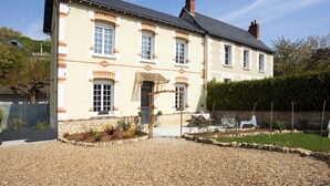 Une maison à deux étages, avec des fondations en pierre, un toit en tuiles et une allée gravillonnée.