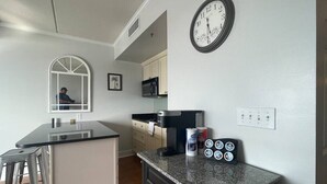 A kitchen with a coffee maker, a clock, and a microwave.