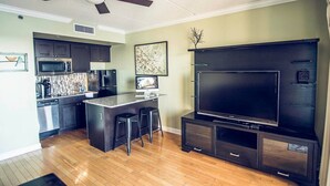 A modern kitchen with dark cabinetry, a microwave, and a dining area with stools. - Water Street Retreat 08 (Wilmington)